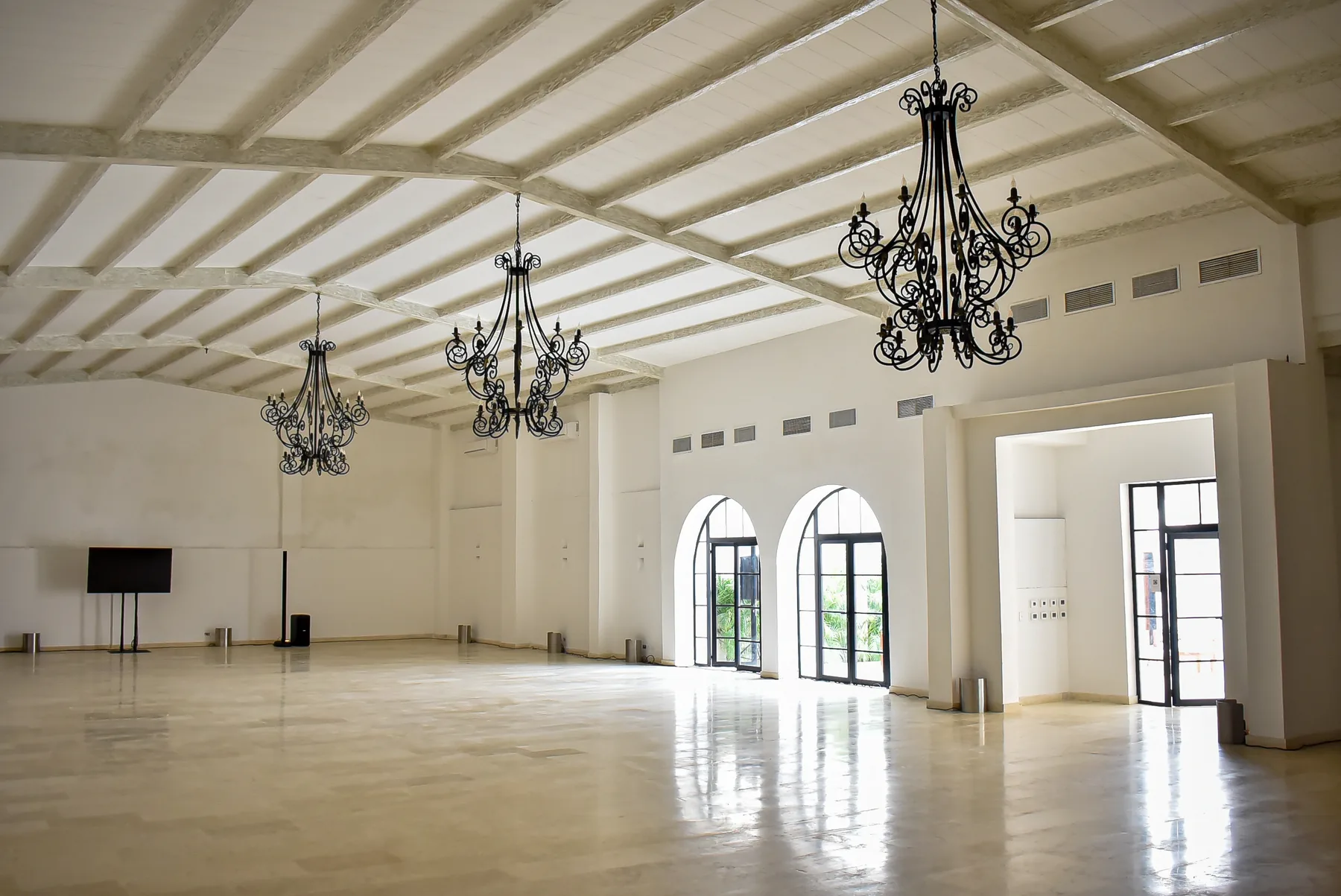 Vista amplia de un salón de Casa Real con arcos, vigas y lámparas colgantes